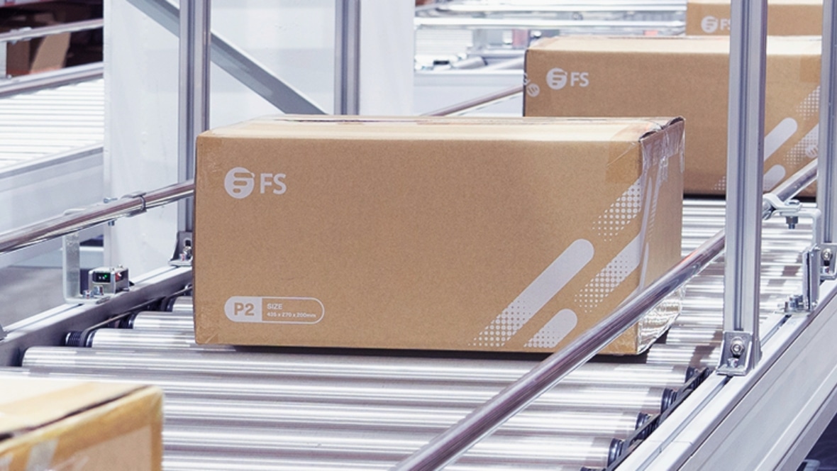 The image shows a box on a conveyor belt in a warehous.